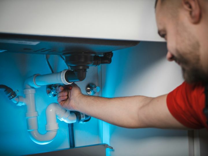 Plumber fixing pipes under a sink